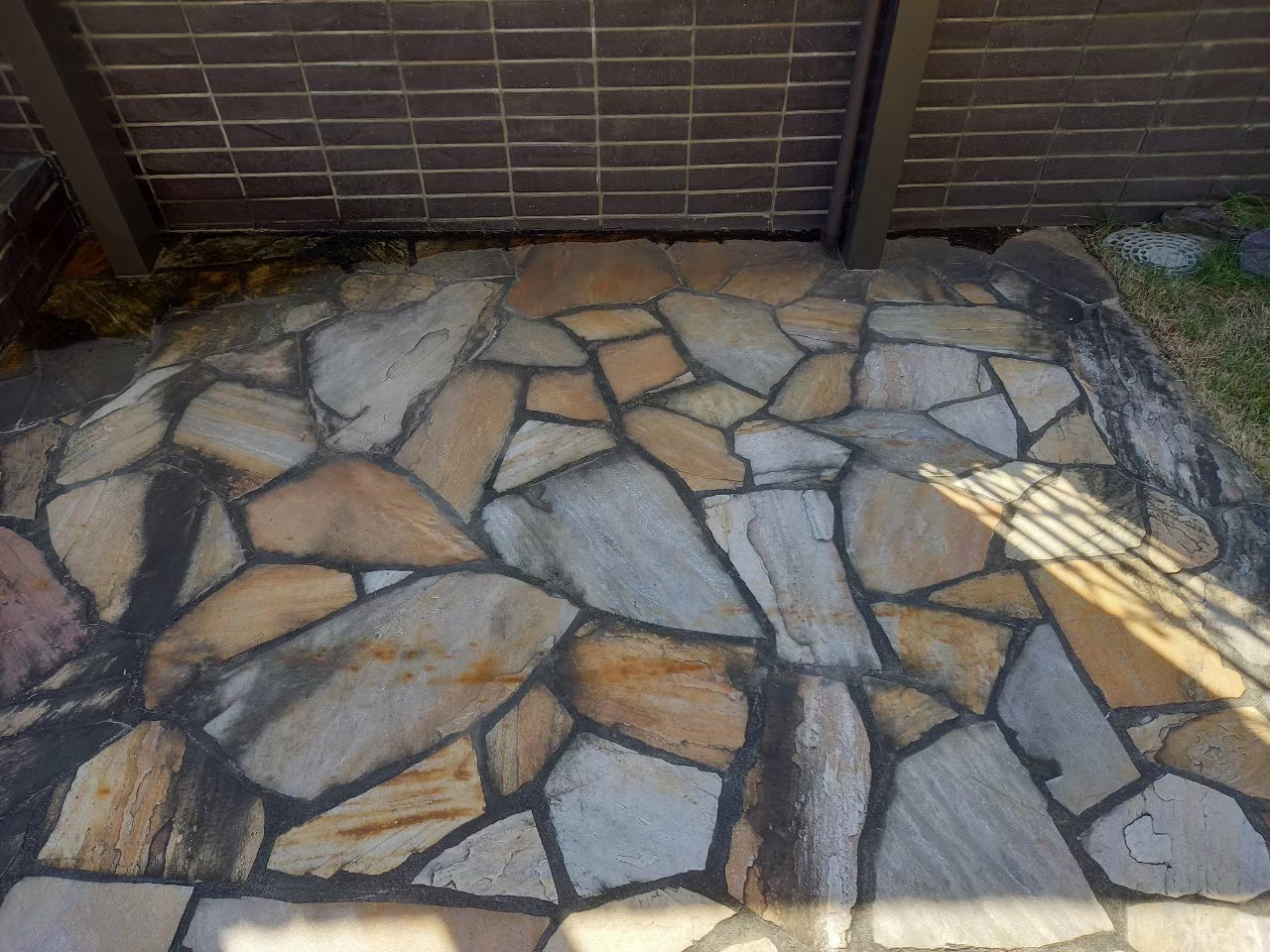 塀沿いの床に黒ずみが広がり、石の色がくすんで見える状態。