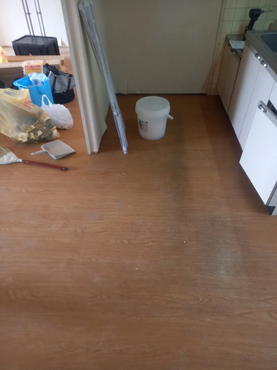施工前のキッチン前。茶系の床に使用感が見られます。