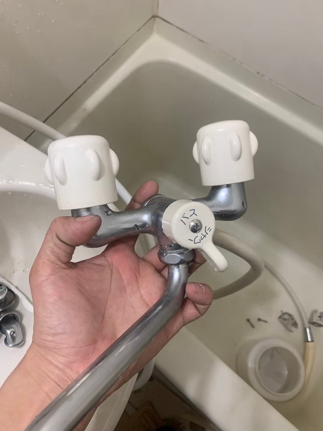 取り外し作業中の、湯と水を別々に回して調整する2ハンドル水栓。